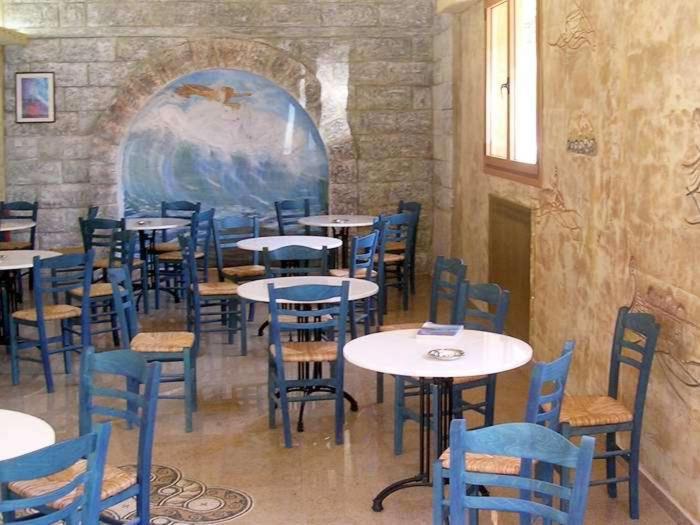 a dining room with tables and blue chairs at Hotel Korakakis Beach in Finikounta