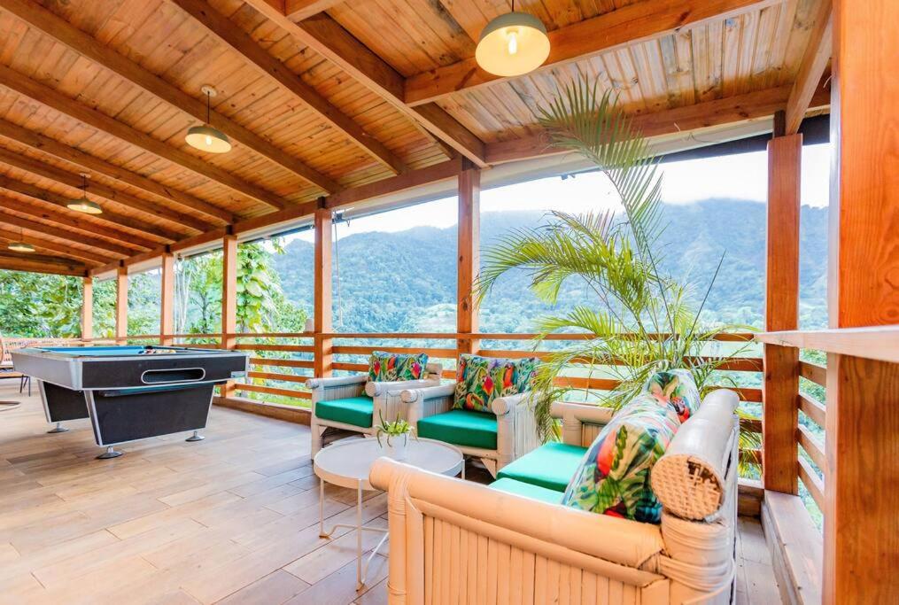un porche cubierto con sofás y mesa de billar en Villa Panorama en La Lomota