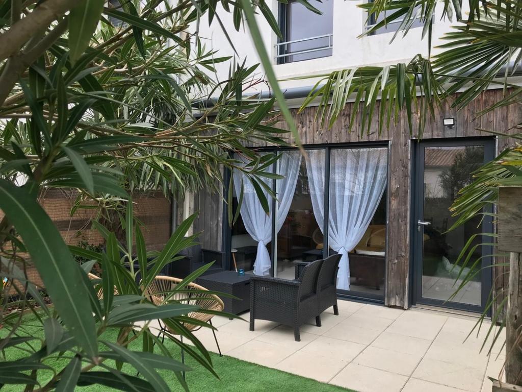 un patio con una silla y cortinas en un edificio en Les PECHERS N 2 MAISON DE 87 m2 à 5mn de La Rochelle de l'île de ré et des plages, en La Genilliere