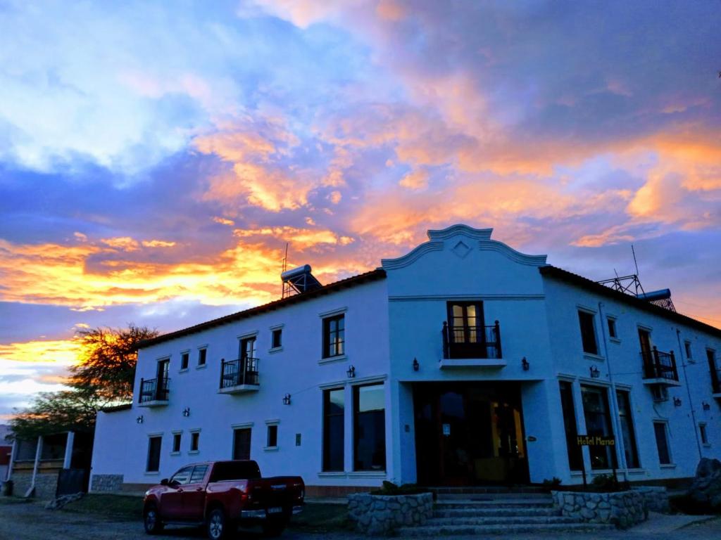 Un camion parcheggiato di fronte a una casa bianca con un tramonto di Hotel Maria Cafayate a San Carlos