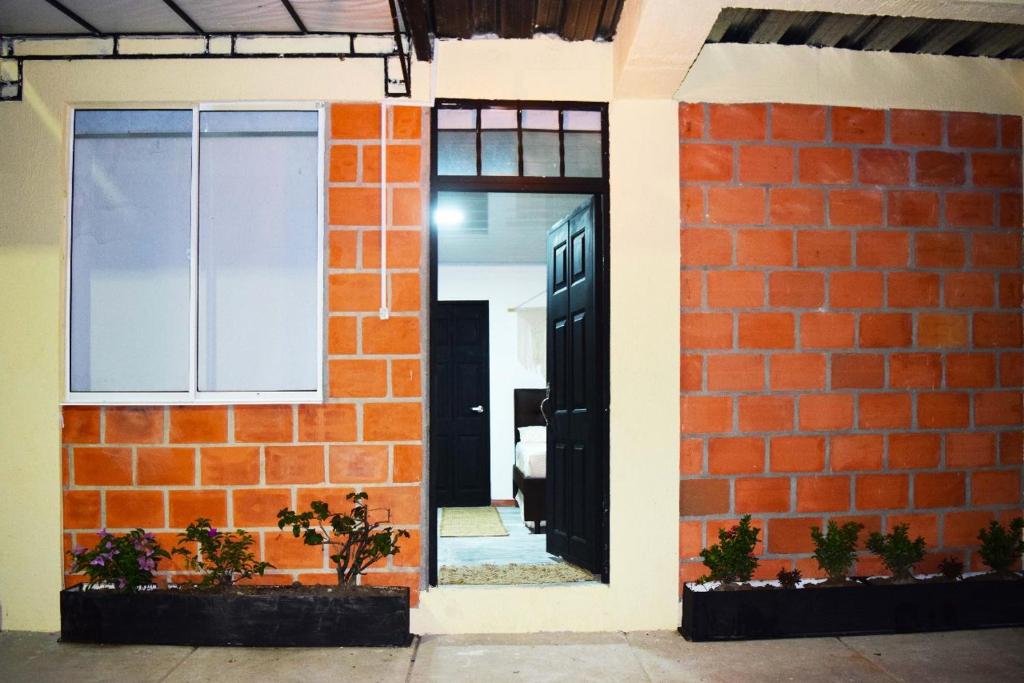 eine Backsteinwand mit einer schwarzen Tür und einem Fenster in der Unterkunft Green Apartment el prado in Girón