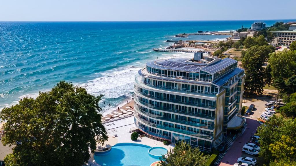 un edificio alto junto a una playa y el océano en SPA Hotel Sirius Beach, en Saints Constantine and Helena