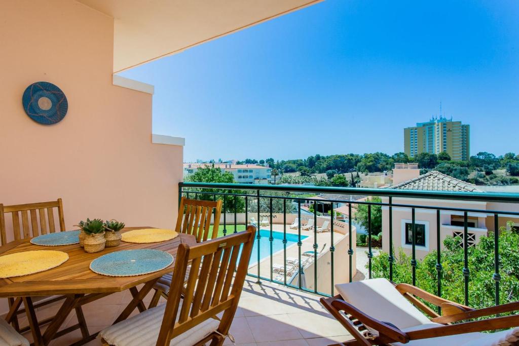 Un balcón con mesa y sillas y una piscina. en Arcos d'Alvor, en Alvor