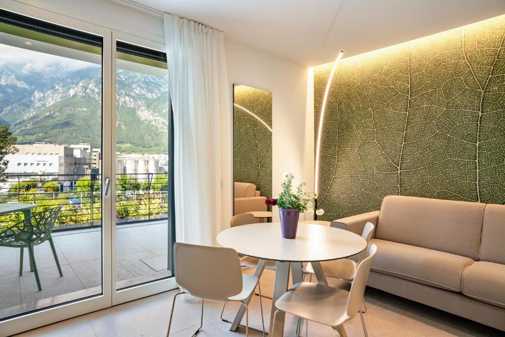 a living room with a table and chairs and a window at Appartamento Midum Garden Nord in Trento