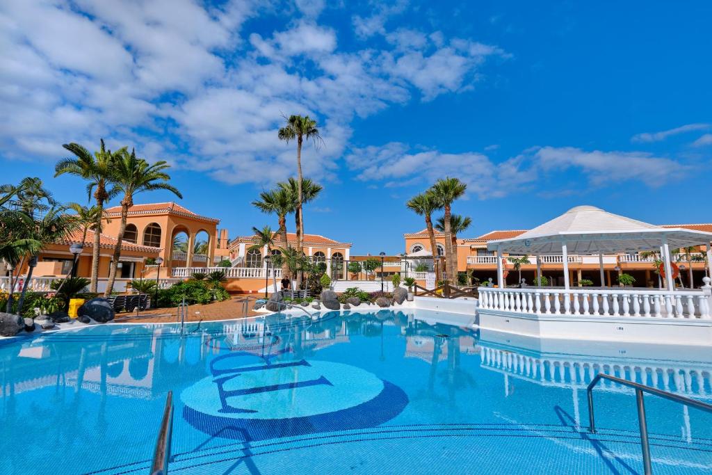 a swimming pool at a resort with palm trees at Home2Book Modern Design Seaview Apt, Pool&Terrace in Playa de las Americas