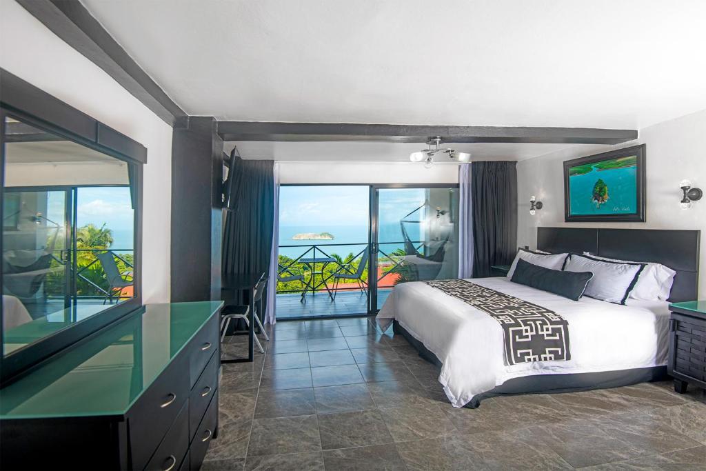 a bedroom with a bed and a view of the ocean at Villa Roca Boutique Resort & Suites - ADULT ONLY in Manuel Antonio