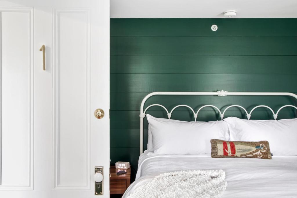 een slaapkamer met een groen hoofdeinde en een wit bed bij Seaside Inn in Tenants Harbor