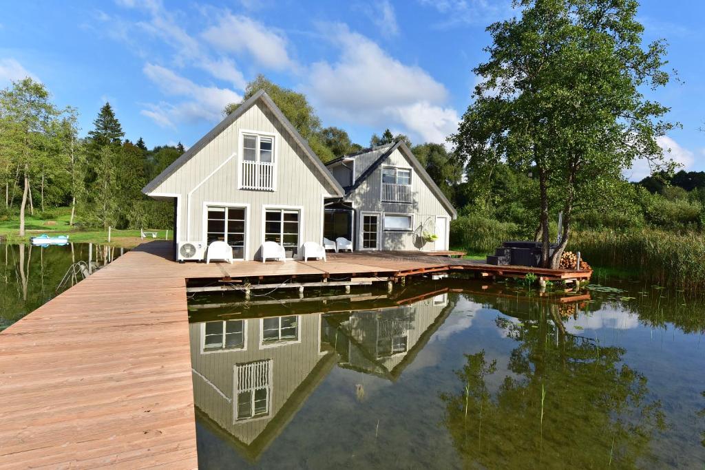 a house on a dock on a body of water at Namelis ant vandens "Giliaus namelis" in Tytuvėnai