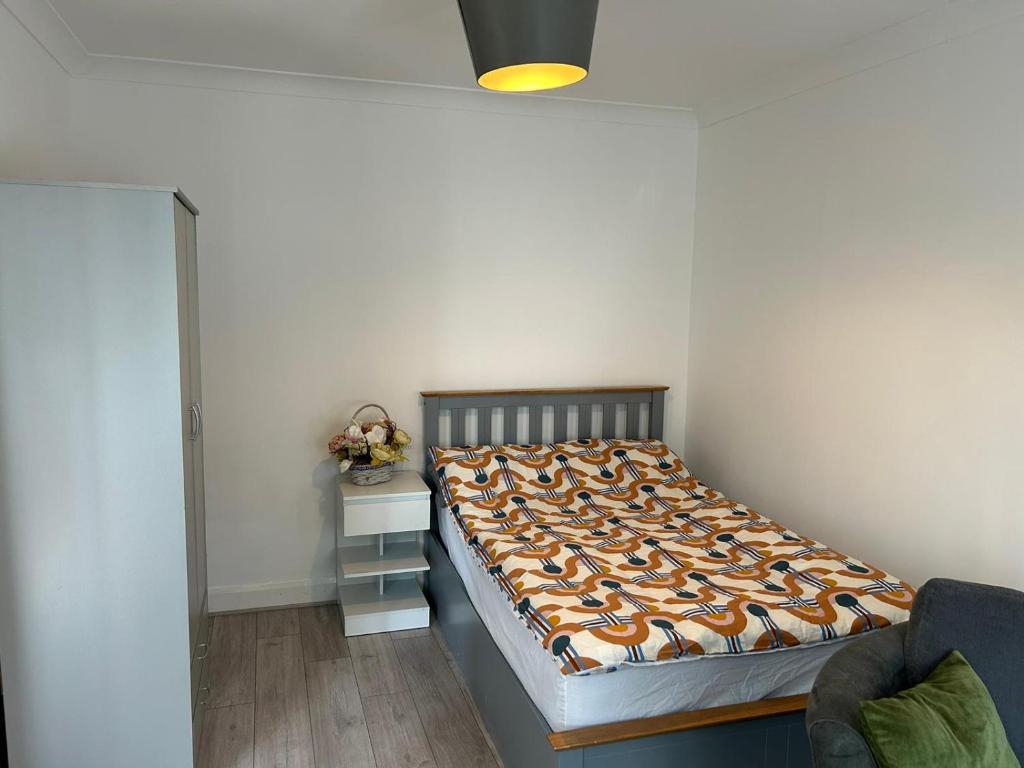 Room in Trumpington London في لندن: غرفة نوم مع سرير و منضدة مع سيد السرير
