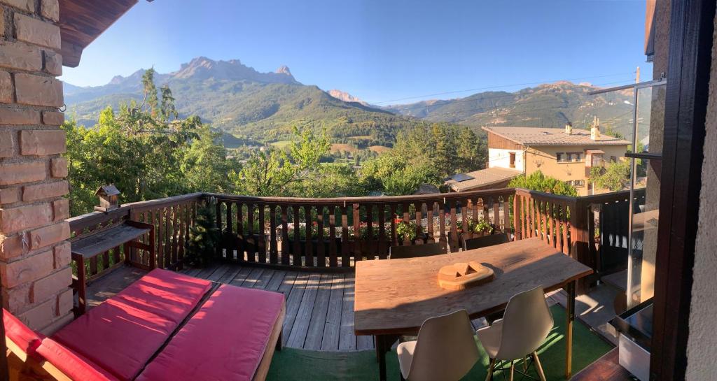 a wooden deck with a table and chairs and mountains at Le Tremplin in Barcelonnette