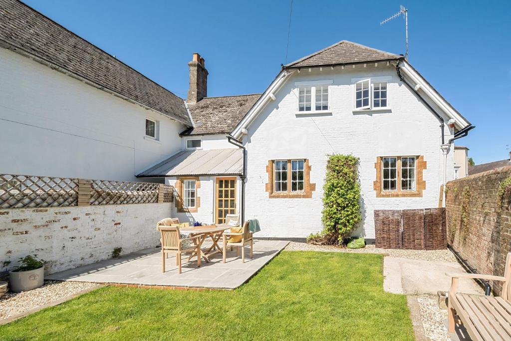une maison blanche avec une table et des chaises dans la cour dans l'établissement The Old Court House, à Cerne Abbas