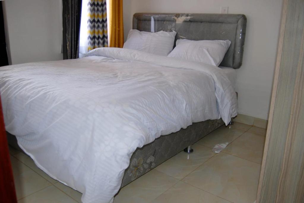 1 cama grande con sábanas y almohadas blancas en Annydo Superior Homes en Nairobi