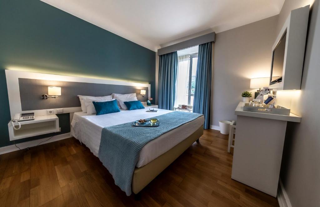 a hotel room with a large bed with blue pillows at Grande Hotel das Caldas da Felgueira in Caldas da Felgueira