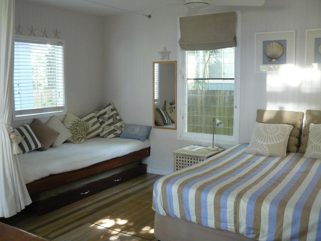 Amity Point的住宿－海窩棚旅館，一间卧室设有一张床和两个窗户。