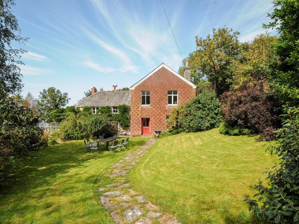 a red brick house with a picnic table in the yard at Carneadon Farmhouse in Launceston