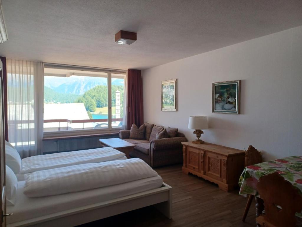 a bedroom with a bed and a couch and a window at Allod Bad 504 in St. Moritz