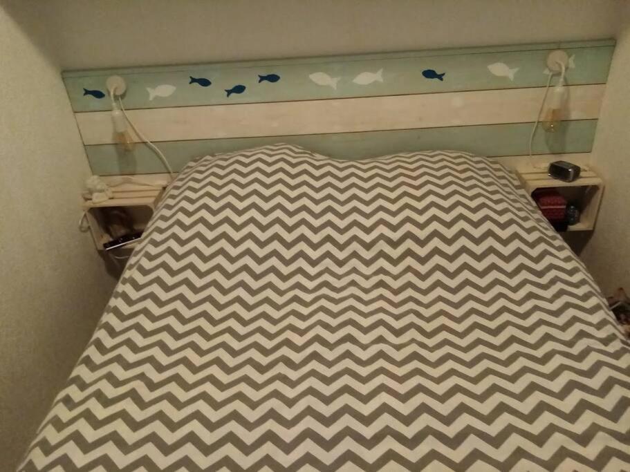 a bed with a brown and white checkered bedspread at Charmant appartement à Sainte Marie la mer (66470) in Sainte-Marie-Plage