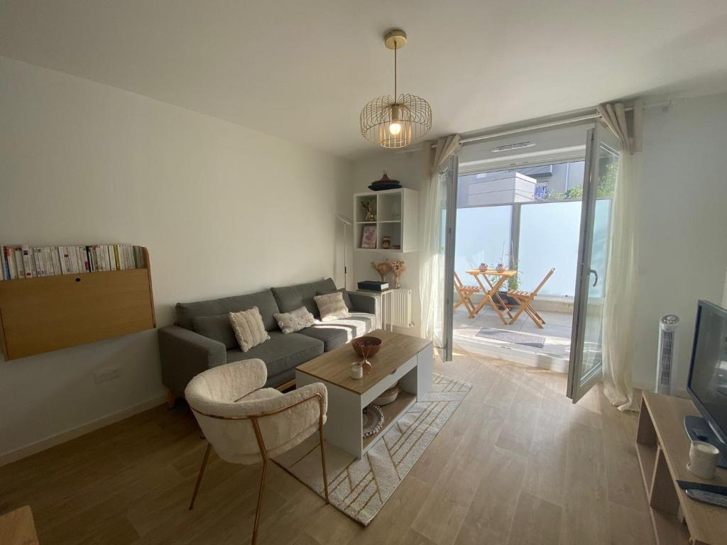 ein Wohnzimmer mit einem Sofa und einem Tisch in der Unterkunft T2 - Coeur de ville - Bezons in Bezons
