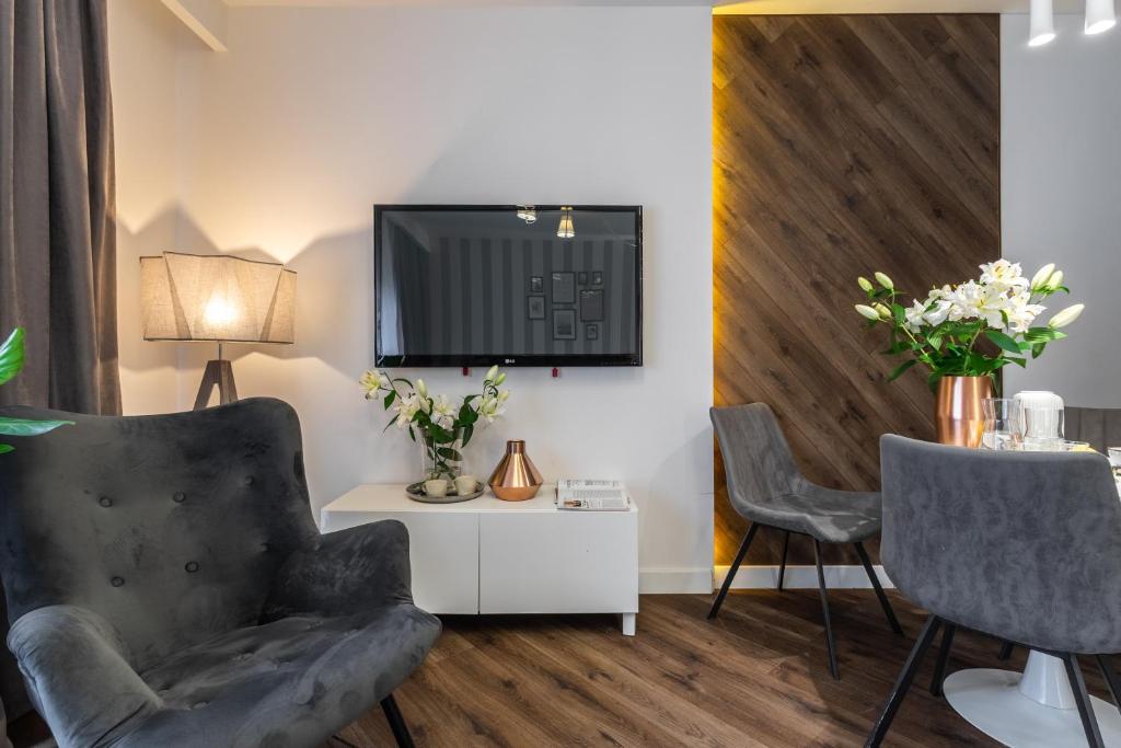 salon z dwoma krzesłami i telewizorem na ścianie w obiekcie Apartment 24 Premium Old Town Wroclaw we Wrocławiu