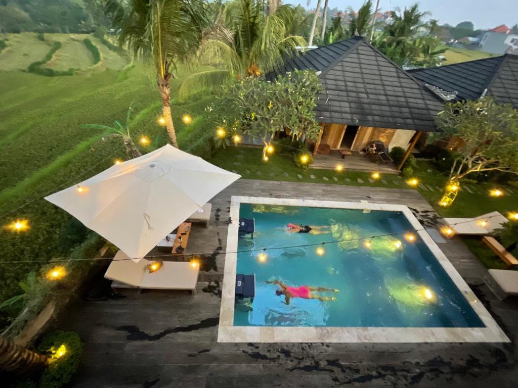 an overhead view of a pool with an umbrella at Balitri - designer villa with shala pool spa in Sukawati