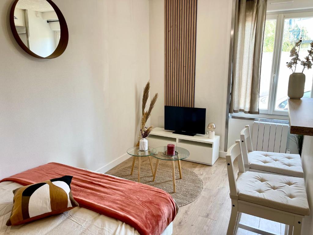 Cette chambre comprend un lit, une table et une télévision. dans l'établissement L’évasion - Studio cosy en centre ville, à Rennes