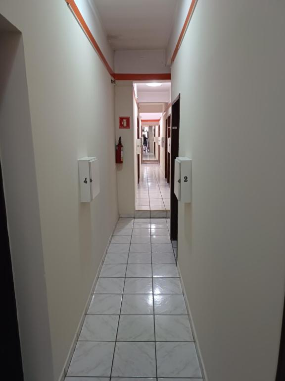 um corredor com paredes brancas e piso em azulejo em Hotel coruja's em São Paulo