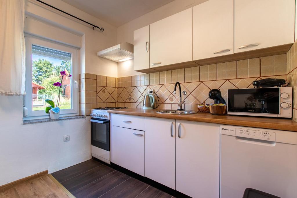 a kitchen with white cabinets and a microwave at Lucija in Lovinac