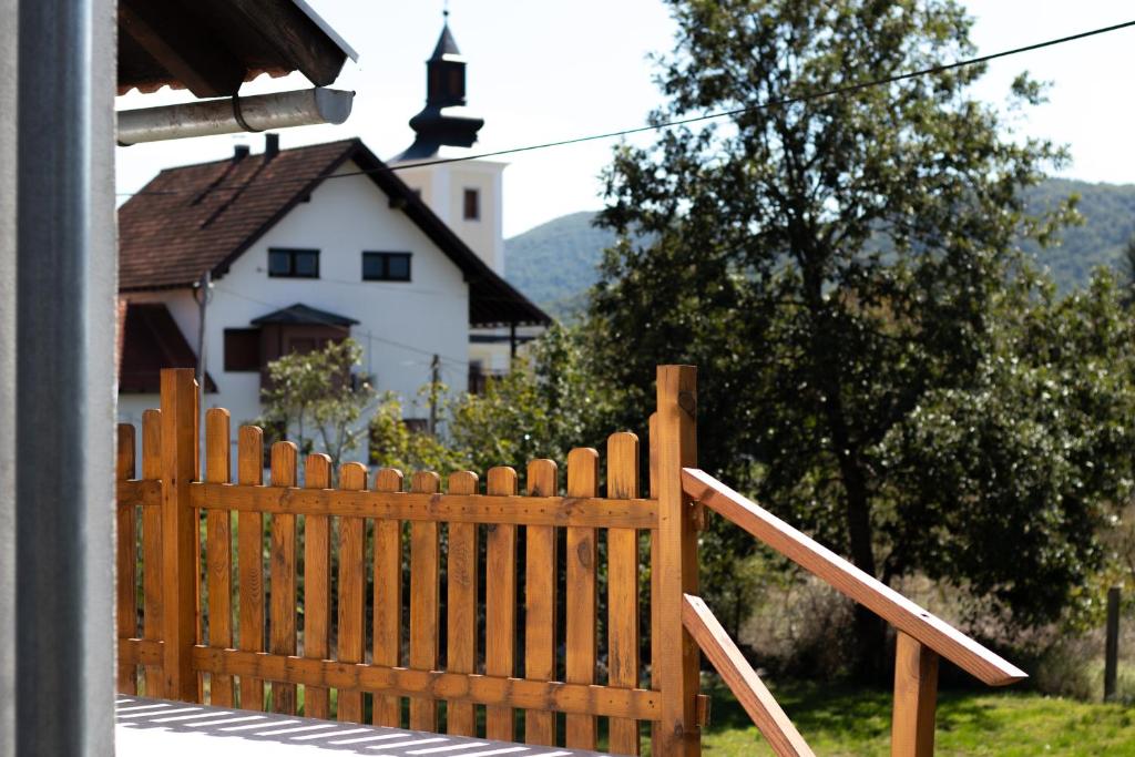 a wooden fence in front of a house with a church at Lucija in Lovinac