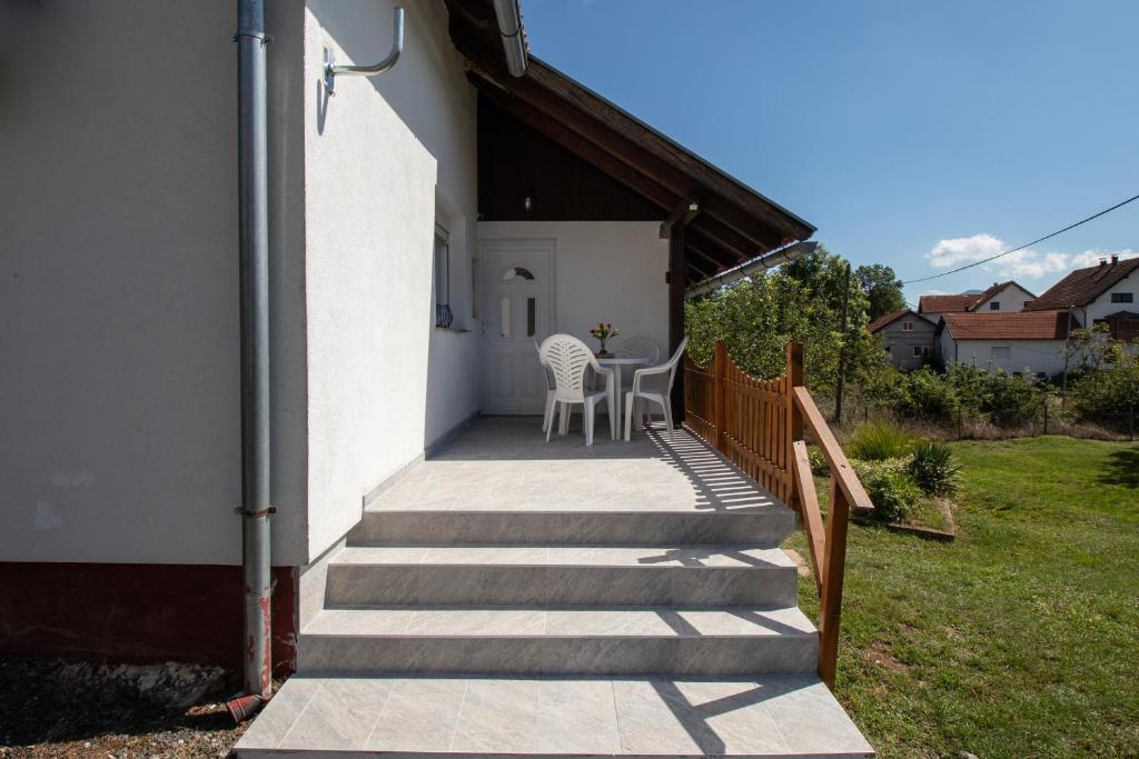 a porch with a table and chairs on the side of a house at Lucija in Lovinac