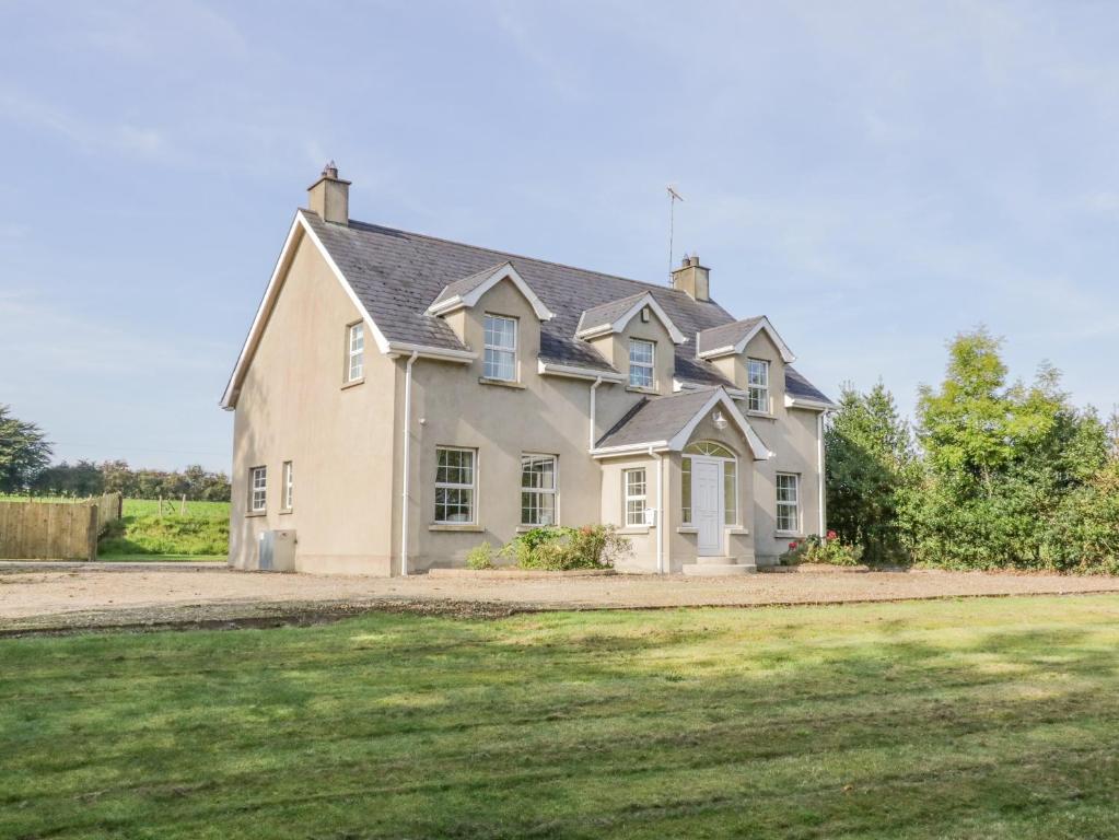 une grande maison blanche avec une cour en herbe dans l'établissement Craiglea Cottage, à Coleraine