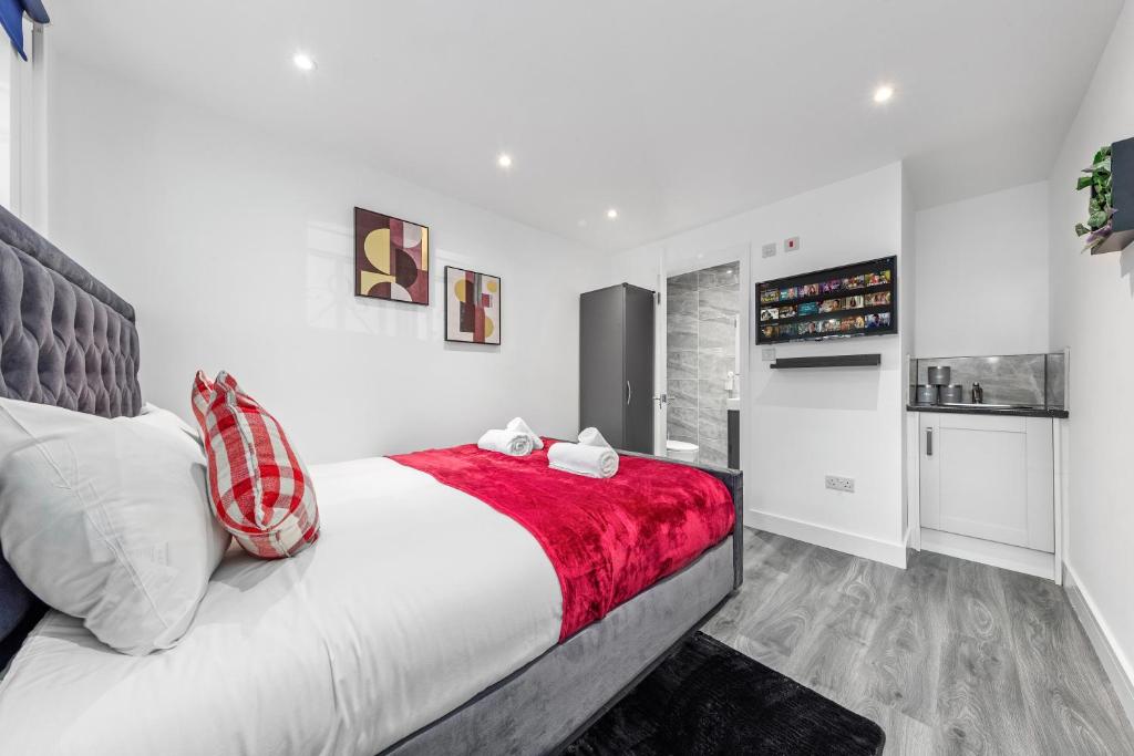 um quarto com uma cama grande e um cobertor vermelho em Serviced Ensuite Room Finsbury Park London N19 em Londres