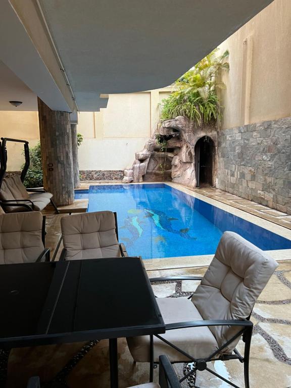 ein großer Pool mit einer Felswand neben einem Pool in der Unterkunft The GlassHouse Pool in Kairo