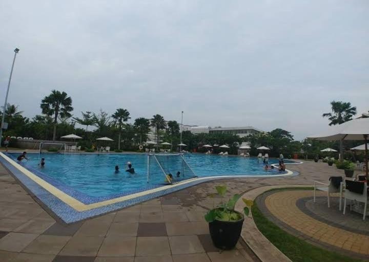 a large swimming pool with people in the water at Barata Hotel by Nature's in Tangerang