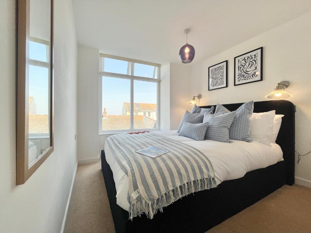 a bedroom with a large bed with a window at Après Beach Apartment Sleeps 4 Penzance in Penzance