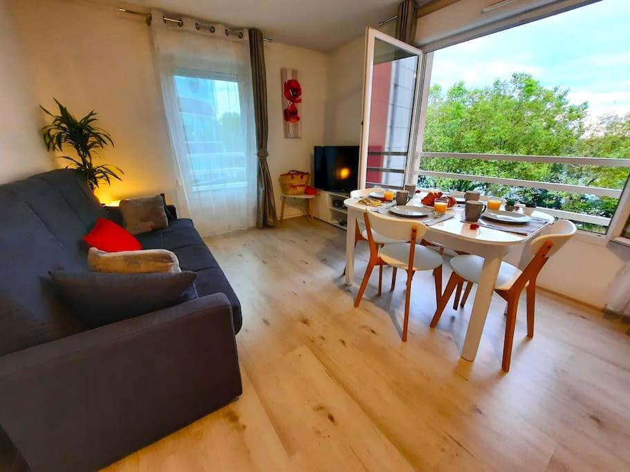 sala de estar con mesa y sofá en Vue panoramique Sur la Seine - 5' Tram - Direct Paris - Parking - Netflix, en Bezons