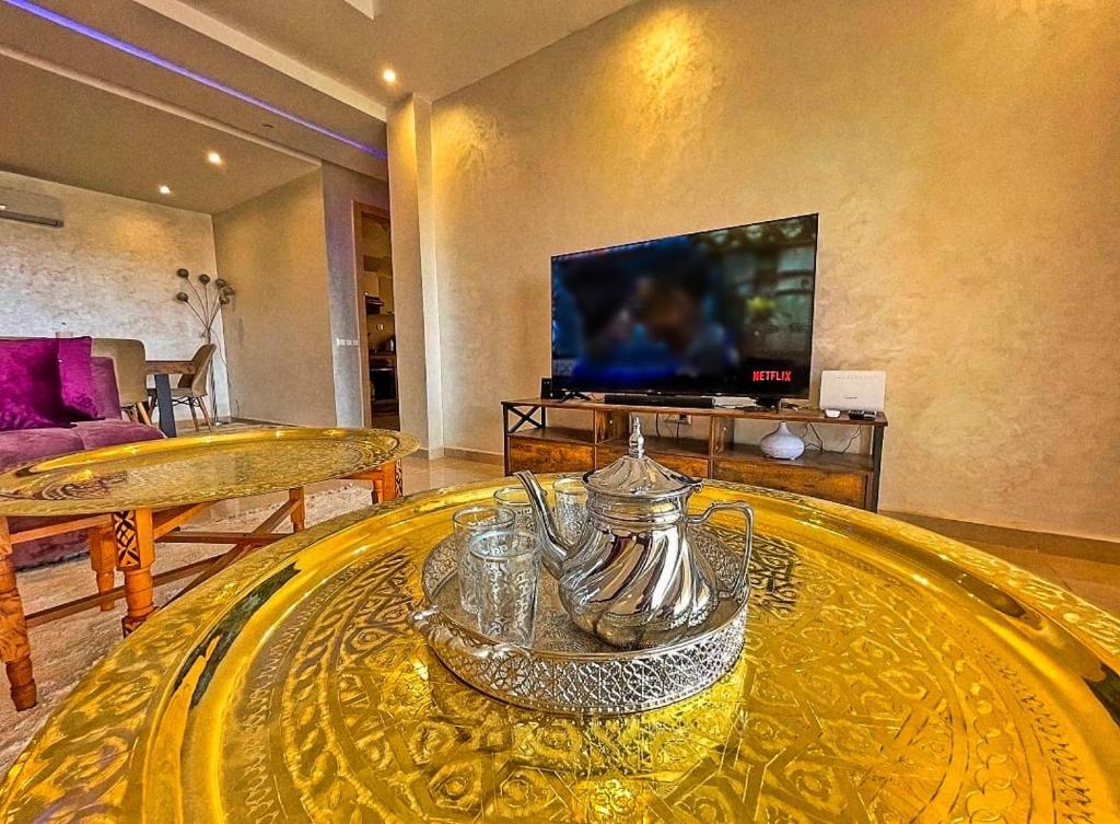 uma sala de estar com uma mesa de vidro e uma televisão em appartement moderne au style beldi résidence au centre de Marrakech avec piscine em Marrakech