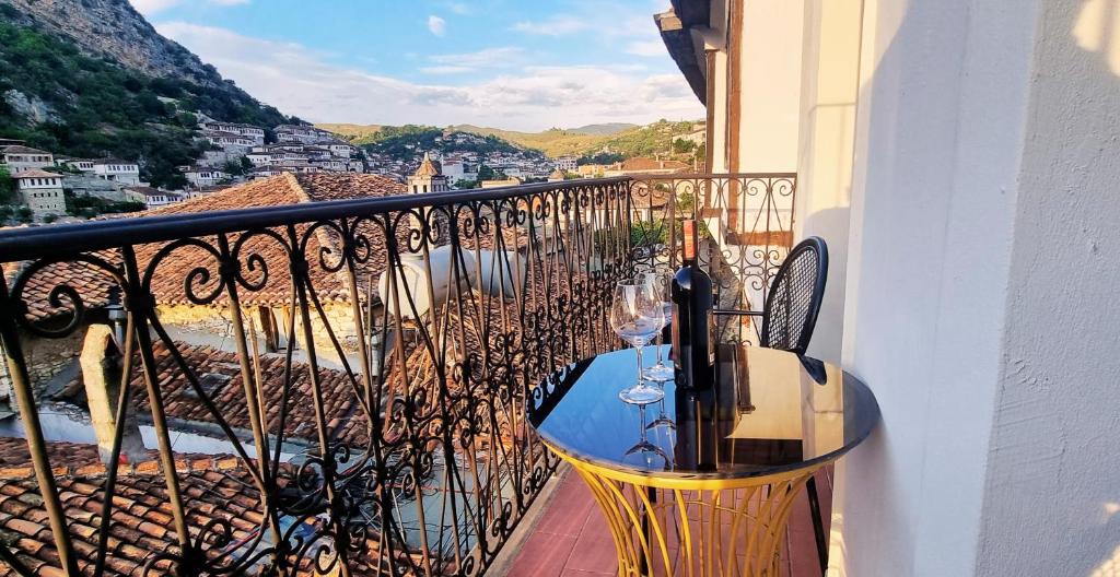 a balcony with a table with wine glasses on it at Hotel Gorica - UNESCO quarter in Berat