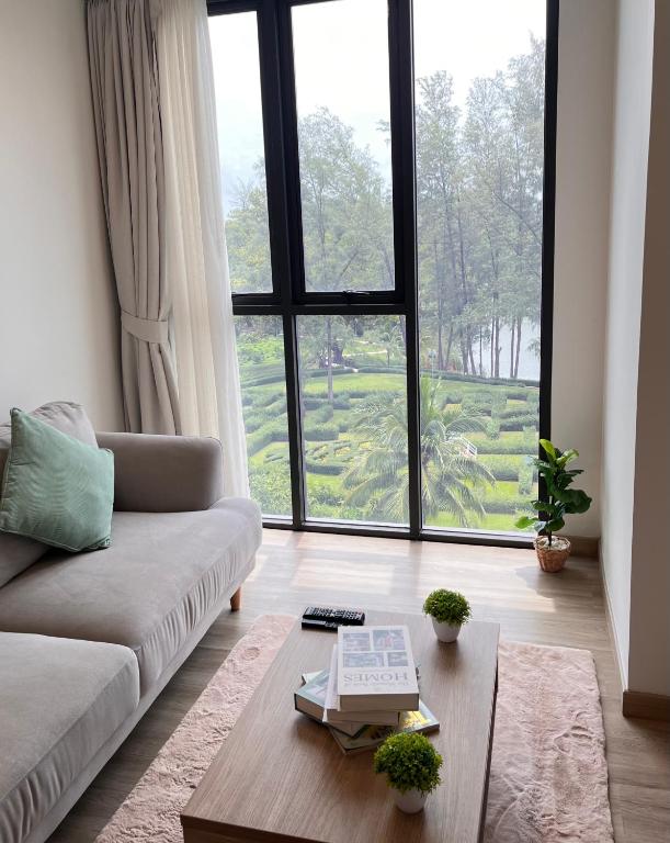 sala de estar con sofá y ventana grande en Sky Park Laguna 1bdr Lake View en Thalang