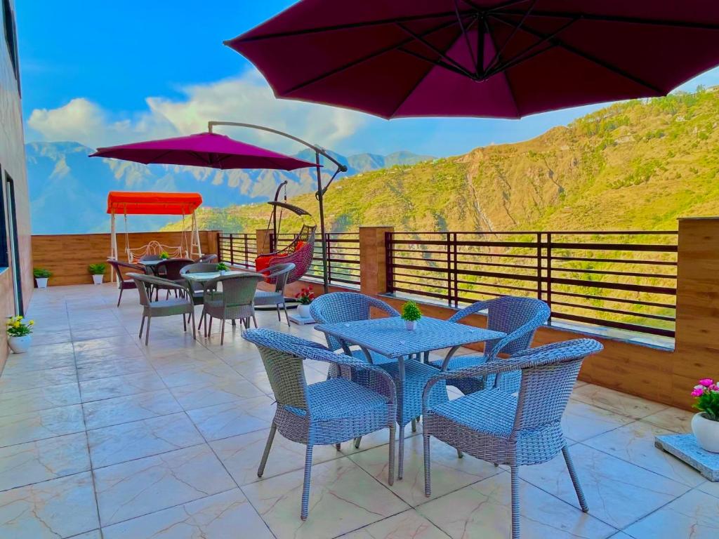 un patio con mesas, sillas y sombrillas púrpuras en River Grand Resort - A Peaceful Stay Kempty Fall Mussoorie en Mussoorie