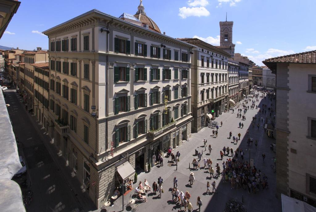 um grupo de pessoas andando por uma rua ao lado de um edifício em Hotel Spadai em Florença