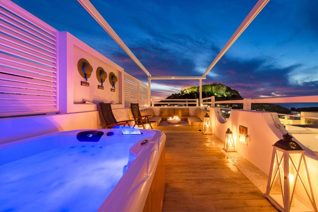 bañera de hidromasaje en el balcón de una casa por la noche en Lindos Allure Villa with Jacuzzi and Acropolis view!!!, en Lindos