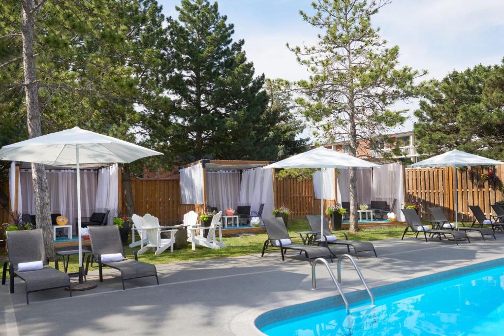 a swimming pool with chairs and umbrellas next to a pool at Sheraton Parkway Toronto North Hotel & Suites in Richmond Hill