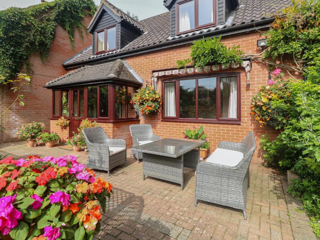 a patio with chairs and a table and some flowers at Walnut Tree Cottage in Great Yarmouth