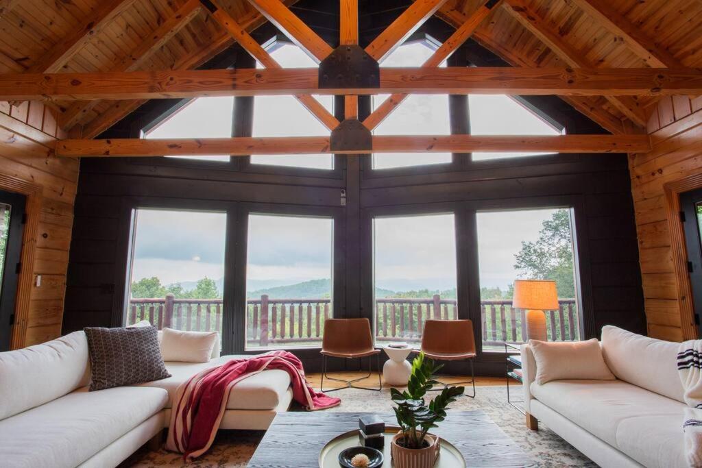 a living room with large windows and white couches at The Ridge: A Modern Cabin in Bostic