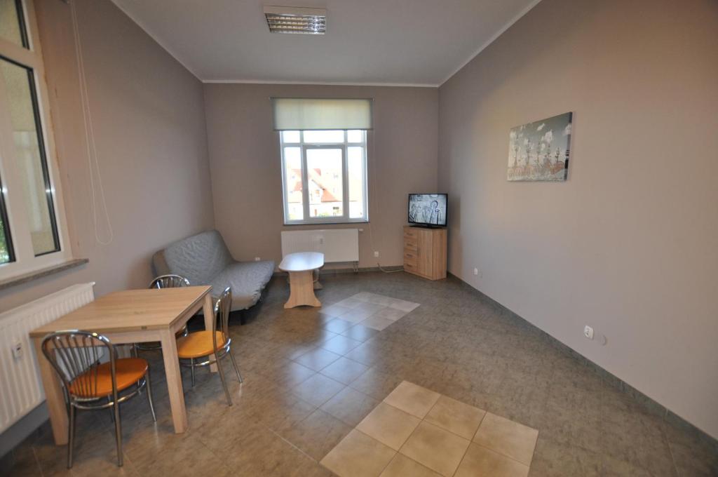 een woonkamer met een tafel en stoelen en een televisie bij Mieszkania Sowiogórskie u podnóża Gór Sowich in Pieszyce