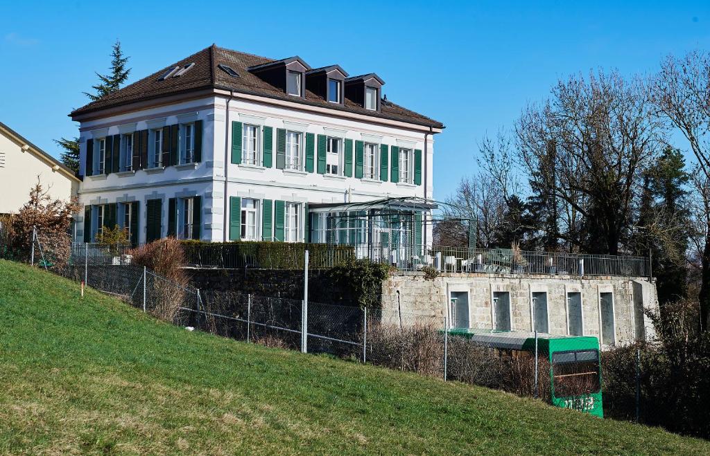 duży biały dom na szczycie wzgórza w obiekcie Hôtel Le Funi de Cossonay w mieście Cossonay