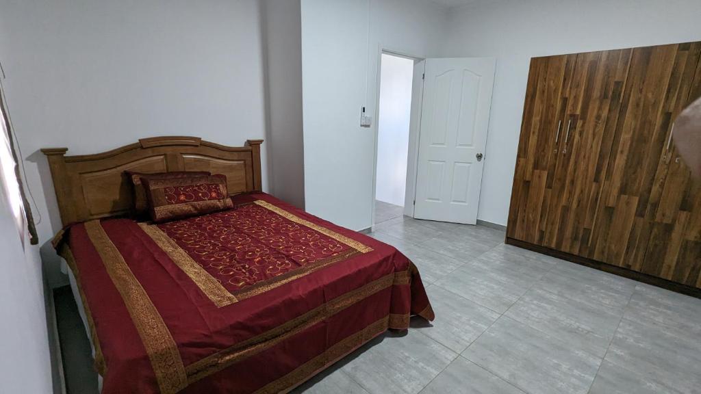 a bedroom with a bed with a red blanket and a door at Haven Green Village in Grand Gaube