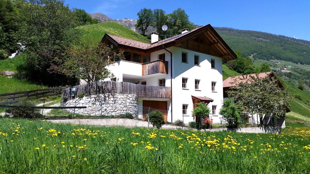 a house on a hill with a field of flowers at Ferienwohnungen Auhaus in Martello