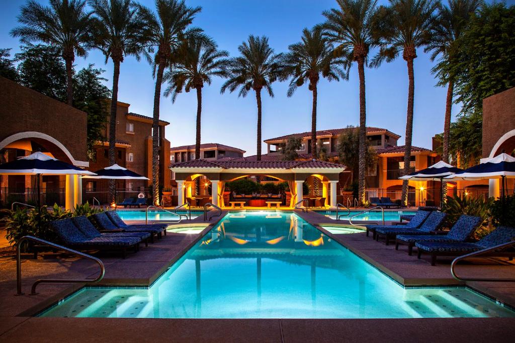 a swimming pool with chairs and palm trees at Luxury Vacation Rentals by Meridian CondoResorts in Scottsdale