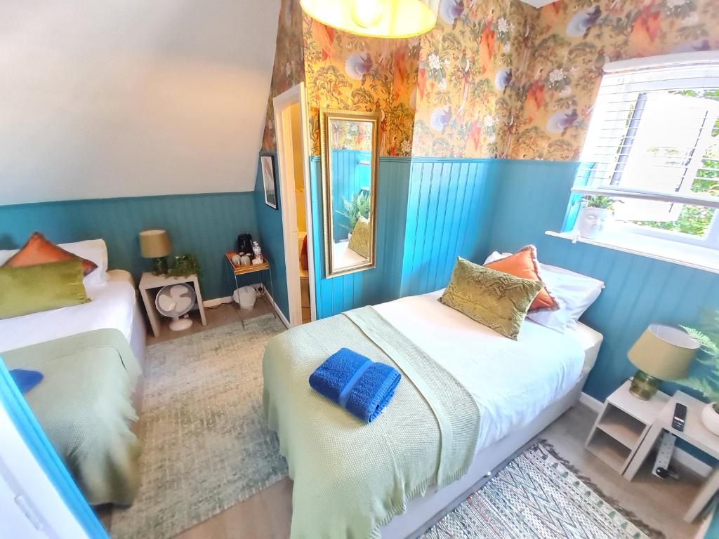 twee bedden in een kamer met blauwe muren bij Birdy Room - Lemur Lodge in Bournemouth